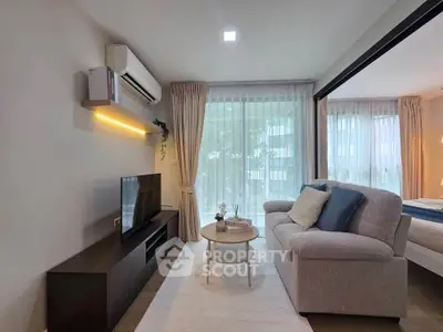 Modern living room with cozy sofa, TV, and large windows offering natural light in a stylish apartment.