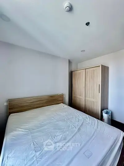 Spacious bedroom with wooden wardrobe and large bed in modern apartment.