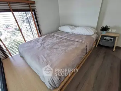 Cozy bedroom with large window and wooden flooring in modern apartment