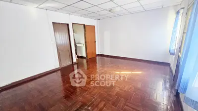 Spacious empty room with wooden flooring and natural light, ideal for customization.