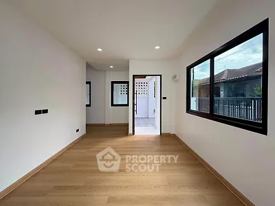Spacious modern room with wooden flooring and large windows, ideal for versatile living space.