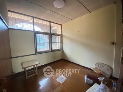 Spacious empty room with wooden flooring and large windows