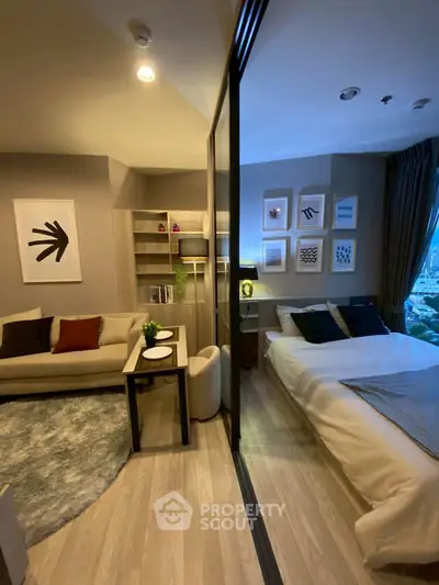 Modern studio apartment with cozy living area and stylish bedroom separated by glass partition.
