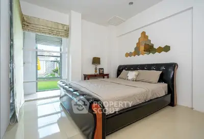 Modern bedroom with stylish decor and garden view, featuring sleek furniture and ample natural light.