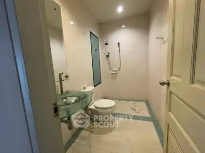 Modern bathroom with glass sink and shower in a minimalist design.