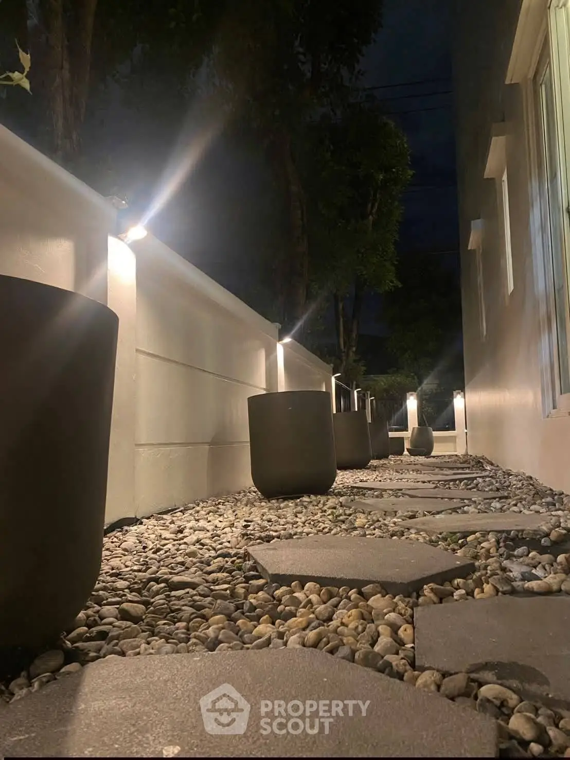 Charming nighttime garden pathway with modern lighting and sleek planters.