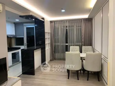 Modern dining area with elegant lighting and open kitchen layout in stylish apartment.