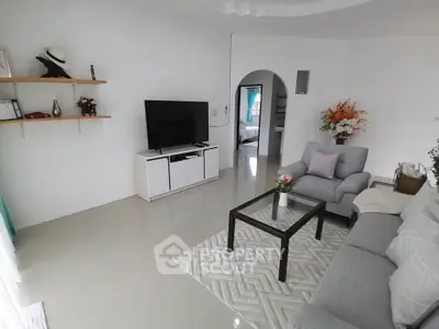 Spacious modern living room with sleek furniture and large TV, perfect for relaxation and entertainment.