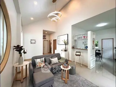 Modern living room with stylish decor and open layout, featuring a cozy gray sofa and elegant lighting.