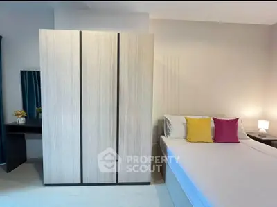 Modern bedroom with sleek wardrobe and colorful pillows, perfect for a cozy living space.