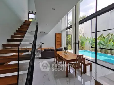 Modern living room with pool view and elegant staircase