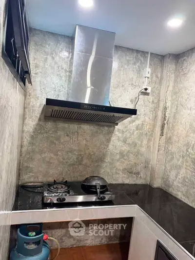 Modern kitchen with sleek gas stove and stylish range hood in compact space.