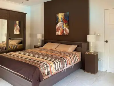 Elegant bedroom with modern decor and stylish artwork above the bed, featuring a large mirrored wardrobe.