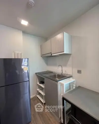 Compact modern kitchen with sleek cabinetry and stainless steel appliances in a cozy apartment.