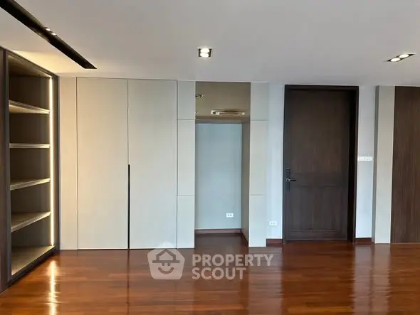 Spacious modern interior with wooden flooring and built-in shelving, ideal for customization.