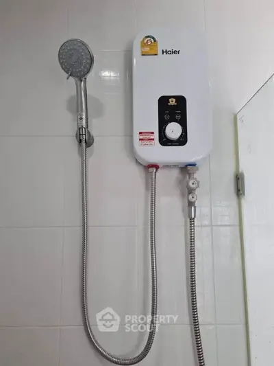Modern bathroom with Haier water heater and shower head on tiled wall.
