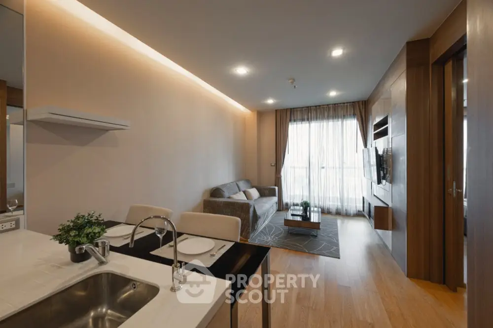 Modern living room with open kitchen, cozy seating, and elegant decor.