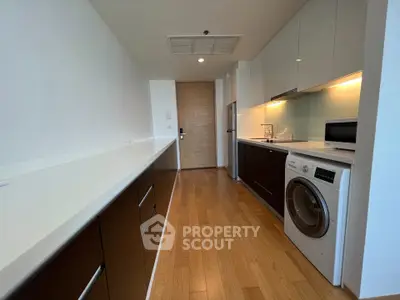 Modern kitchen with sleek cabinetry, washing machine, and microwave in a stylish apartment.