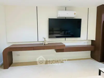 Modern living room with sleek wooden console and mounted TV, featuring minimalist decor and air conditioning.