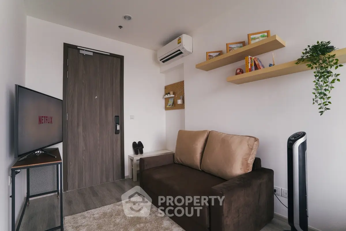 Cozy living room with modern decor, featuring a comfortable sofa, wall-mounted shelves, and a flat-screen TV.