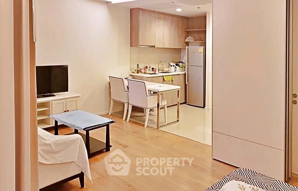 Modern open-layout living room with kitchen, featuring wooden flooring and contemporary furniture.