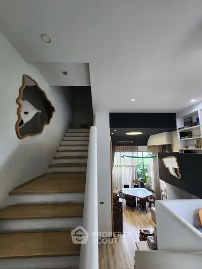 Modern open-plan living area with unique wall art and staircase