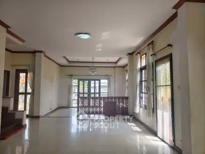 Spacious living room with large windows and elegant wooden accents, perfect for natural light and modern living.