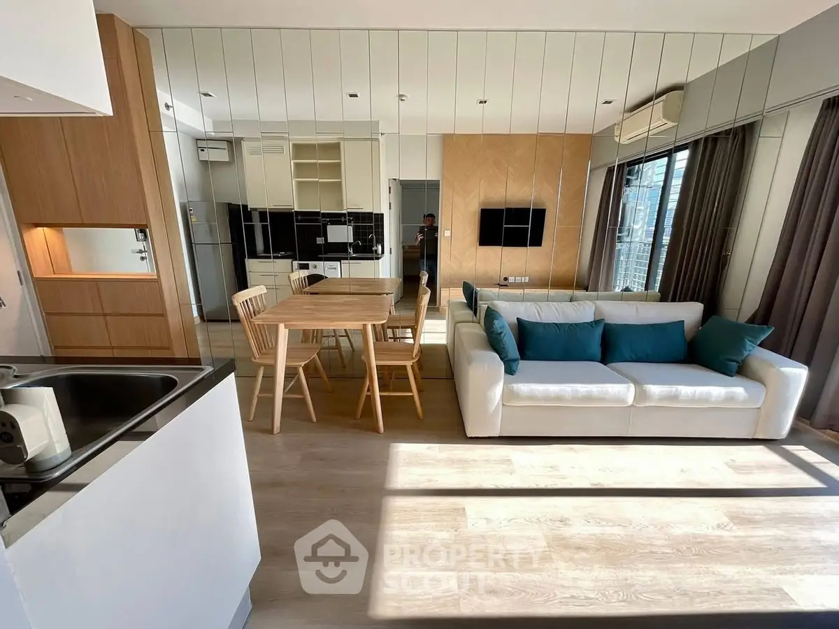 Modern open-plan living room with stylish kitchen and dining area, featuring sleek design and ample natural light.