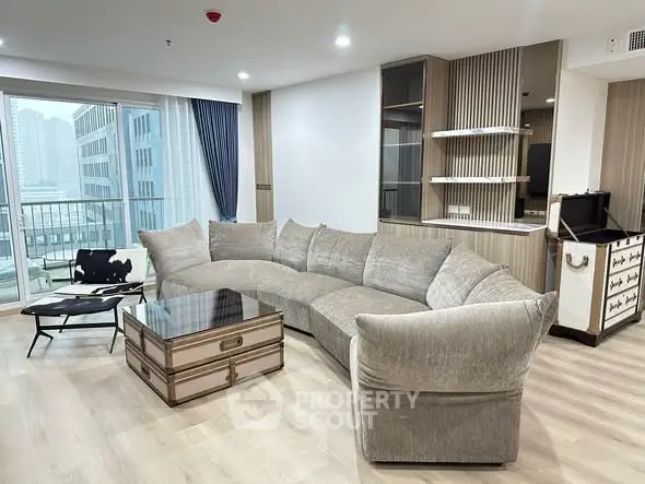 Luxurious modern living room with plush curved sofa and city view balcony in high-rise apartment.