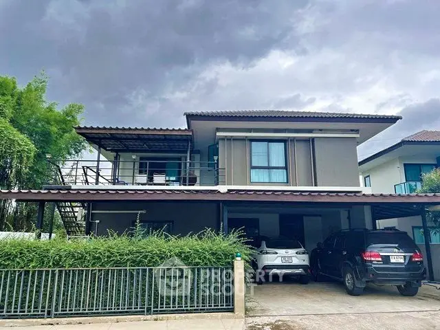 Modern two-story house with carport and lush greenery under a cloudy sky.