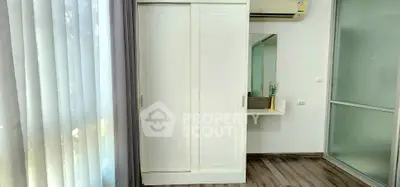 Modern bedroom with sleek wardrobe and air conditioning, featuring elegant flooring and natural light.