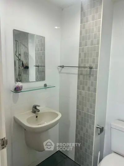 Modern bathroom with sleek sink and tiled shower area in contemporary apartment.
