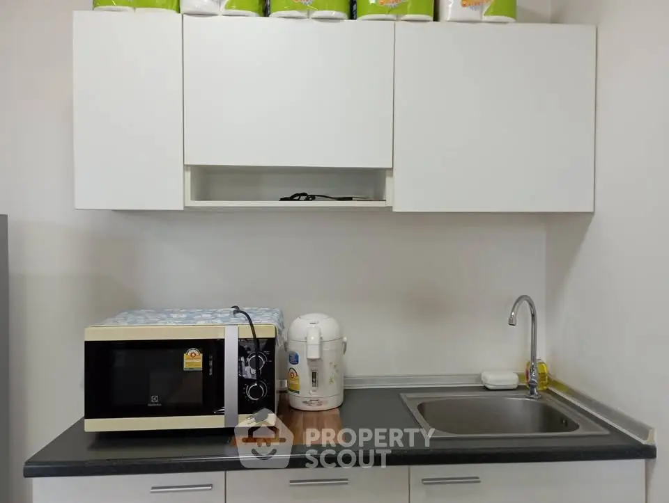 Modern kitchen with sleek cabinets, microwave, and sink, perfect for compact living spaces.