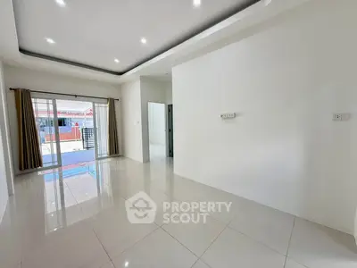 Spacious modern living room with glossy tiled floors and sliding glass doors leading to a patio.