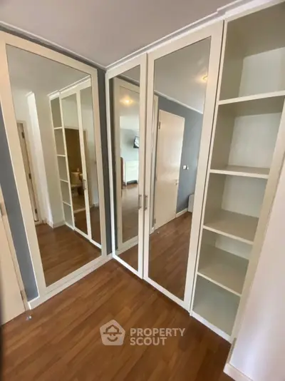 Spacious walk-in closet with mirrored doors and ample shelving in modern apartment.