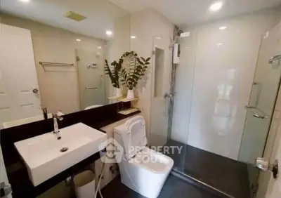 Modern bathroom with glass shower and sleek fixtures in a contemporary home.