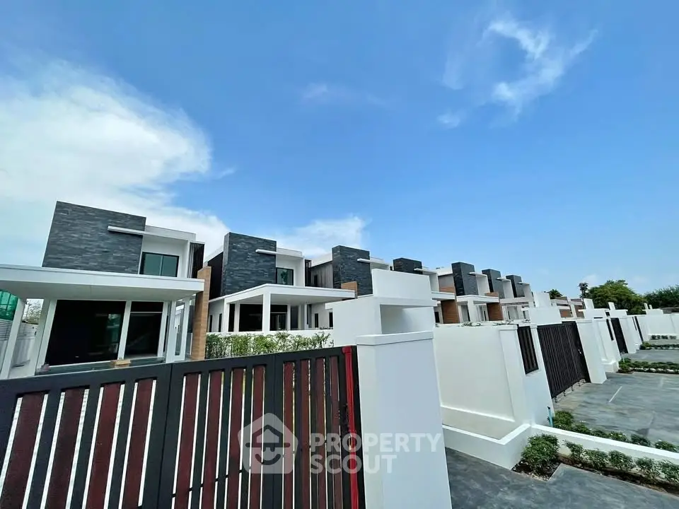 Modern row of stylish townhouses with sleek design and spacious layout under a clear blue sky.