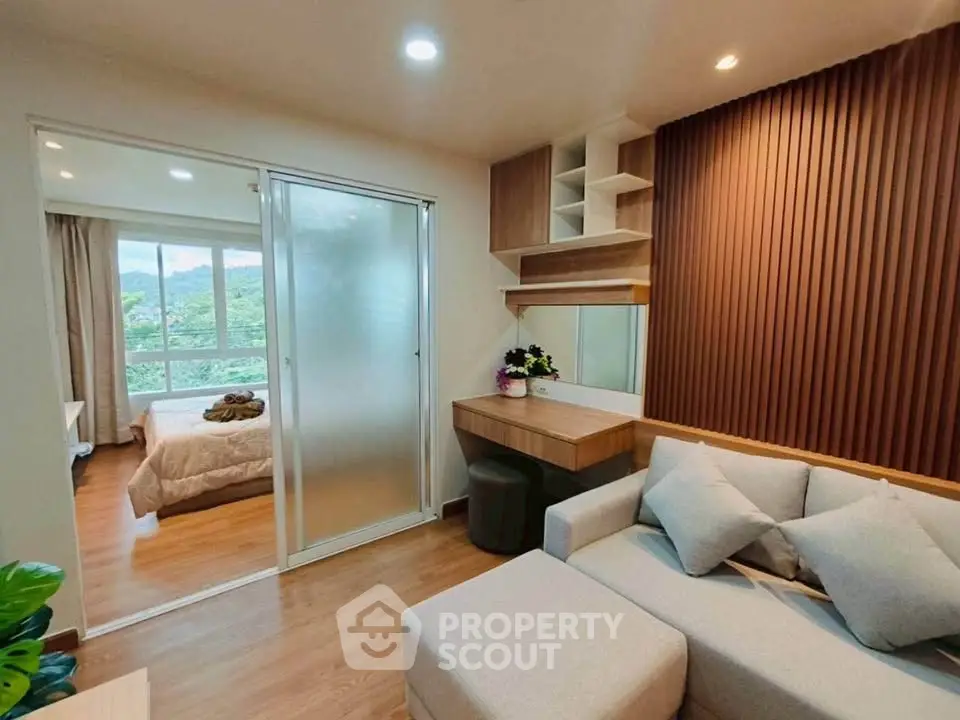 Modern living room with cozy sofa and stylish decor, adjacent to a bedroom with scenic window view.