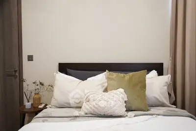 Cozy bedroom with plush pillows and neutral decor, perfect for relaxation and comfort.