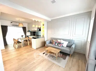 Modern open-plan living room with stylish kitchen and dining area, featuring elegant decor and ample natural light.