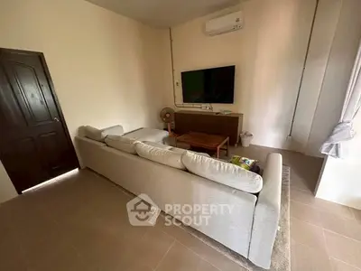 Cozy living room with modern sofa, wall-mounted TV, and air conditioning, perfect for relaxation.