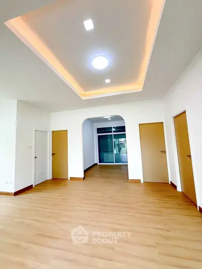Spacious modern living room with elegant ceiling lighting and wooden flooring.