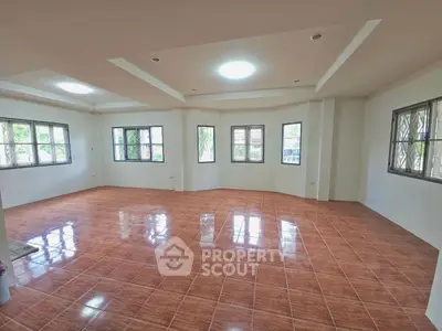 Spacious living room with large windows and tiled flooring, perfect for natural light and comfort.