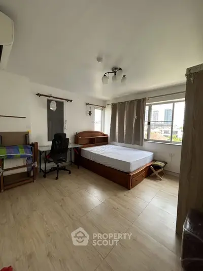 Spacious bedroom with city view, featuring modern furniture and ample natural light.