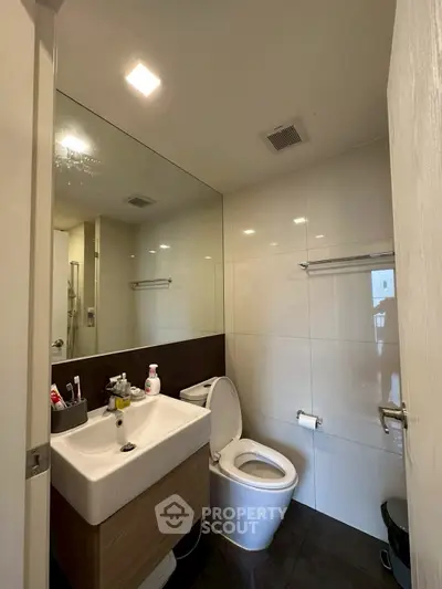 Modern bathroom with sleek fixtures and large mirror in a contemporary apartment.