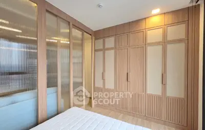 Spacious bedroom with elegant wooden wardrobe and frosted glass sliding doors
