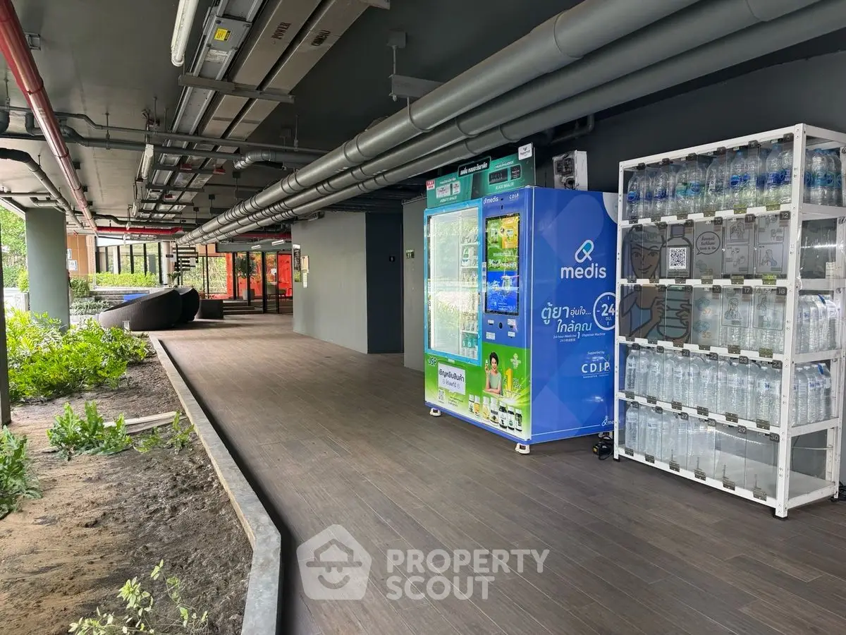 Modern building entrance with vending machines and water bottles, sleek design and greenery.