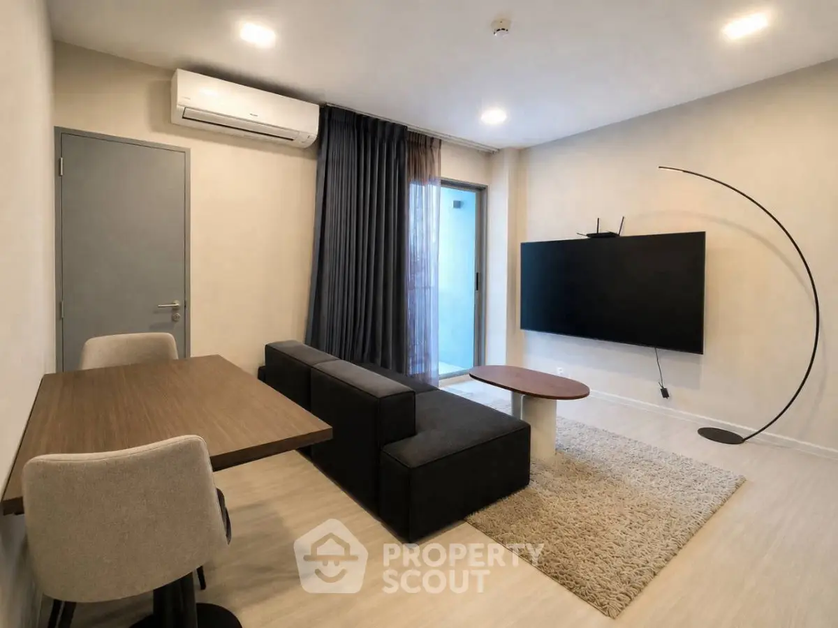 Modern living room with sleek furniture and large TV, featuring a minimalist design and cozy atmosphere.