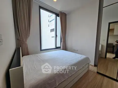 Modern bedroom with large window and minimalist design in urban apartment.