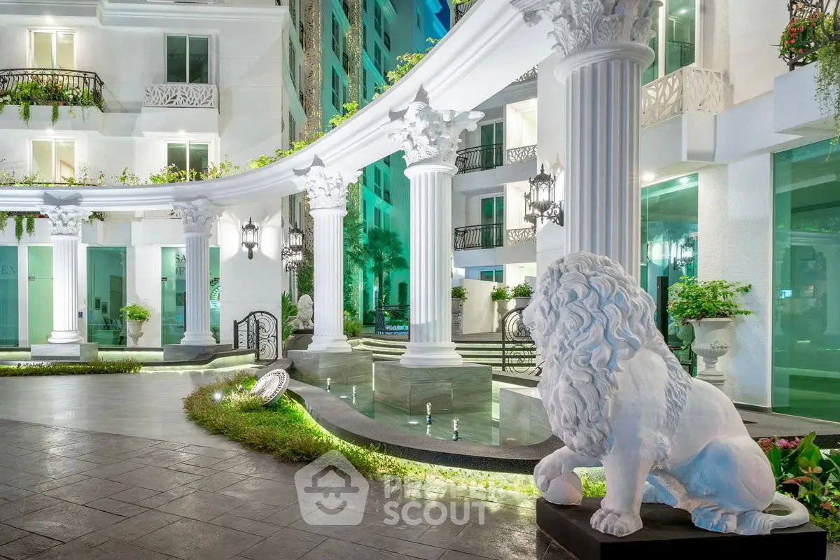 Luxurious entrance with grand columns and lion statue in upscale residential building.